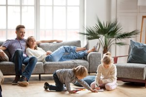 junge Eltern auf dem Sofa, Kinder spielen auf dem Boden