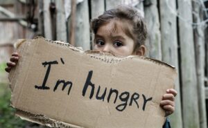Kind hält ein Schild mit der Aufschrft "I'm hungry" in den Händen