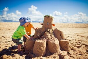zwei Kleinkinder bauen gemeinsam eine Sandburg