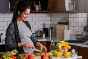 Schwangere Frau bereitet gesundes Essen zu