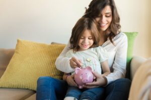 Mutter wirft zusammen mit ihrer Tochter Geld in ein Sparschwein