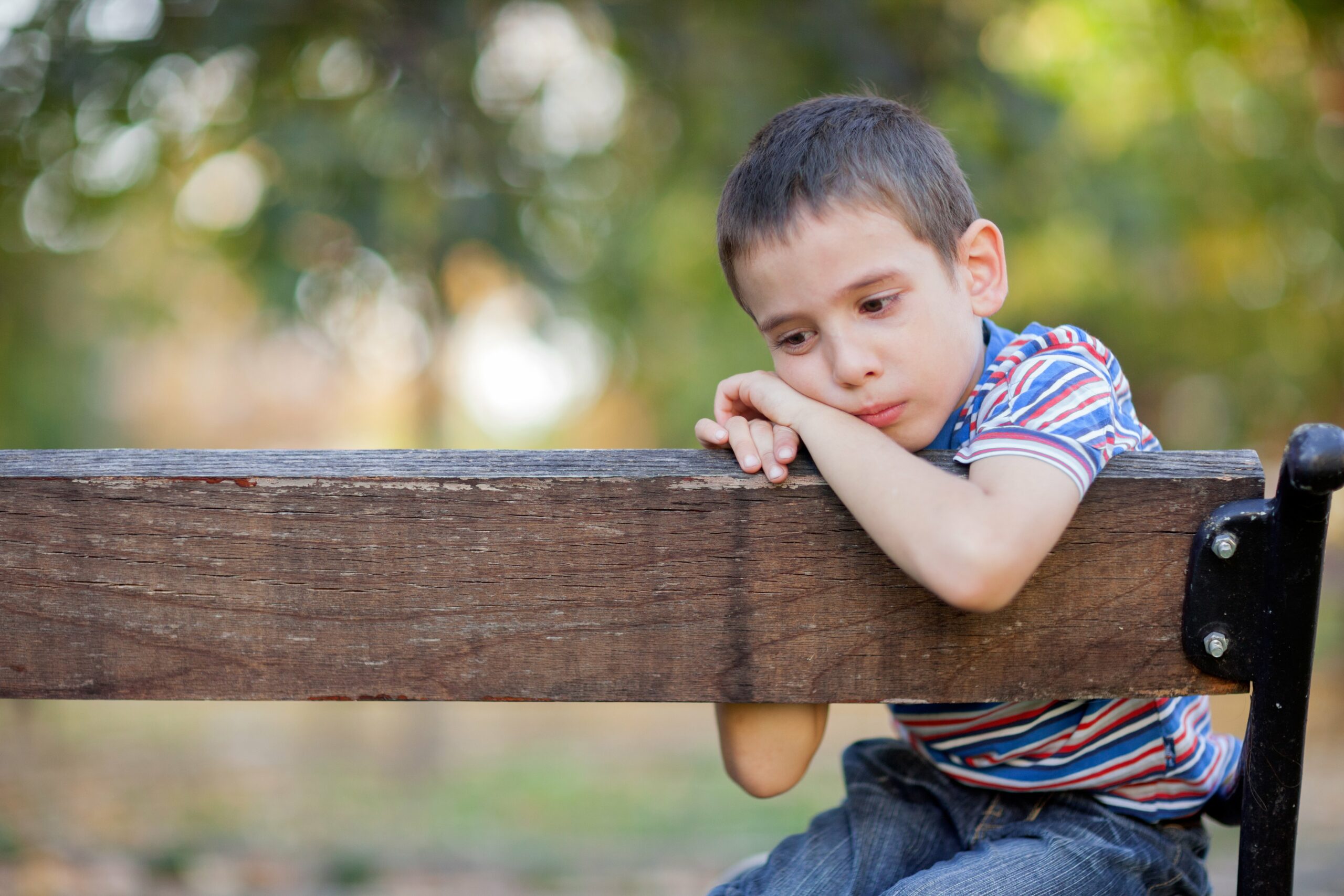 trauriges kind sitzt auf einer bank.
