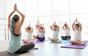 eine frau unterrichtet kinder im yoga