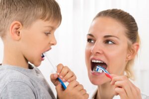 Mutter übt mit ihrem Sohn das Zähneputzen